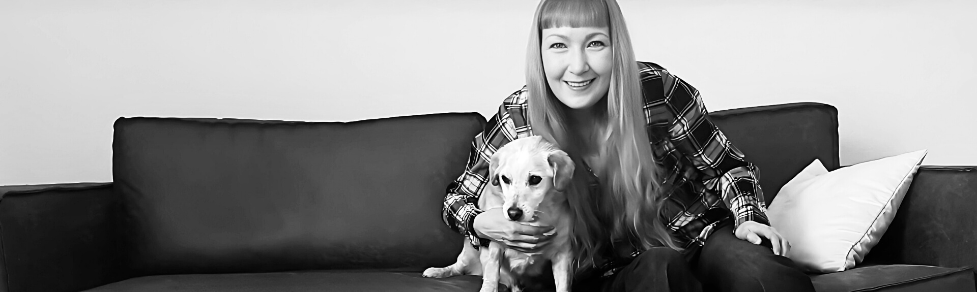 Ein schwarz-weißes Foto der Webtexterin und Webdesignerin Yvonne Flöper, die mit ihrem Hund auf der Couch sitzt.